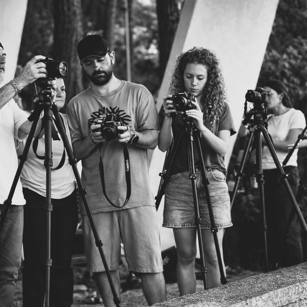 Photographers at a workshop, tripods planted, cameras held in hand