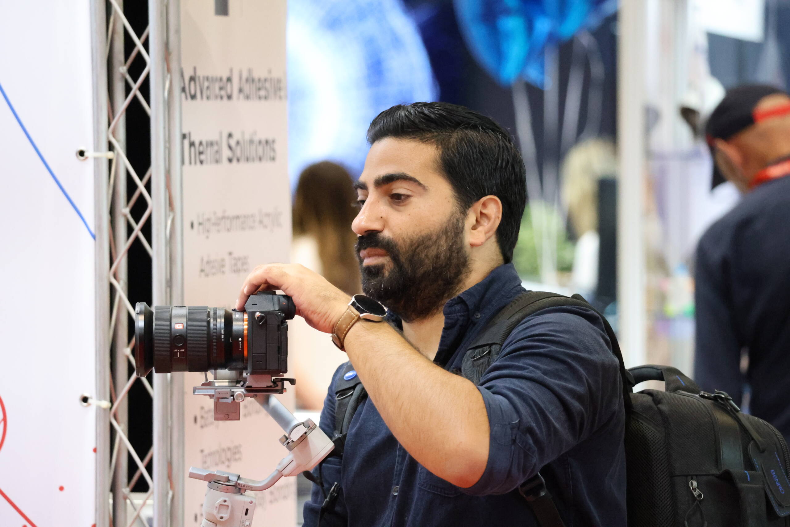 Photographer balancing a Sony camera on a DJI RS 4 Mini gimbal at a trade show