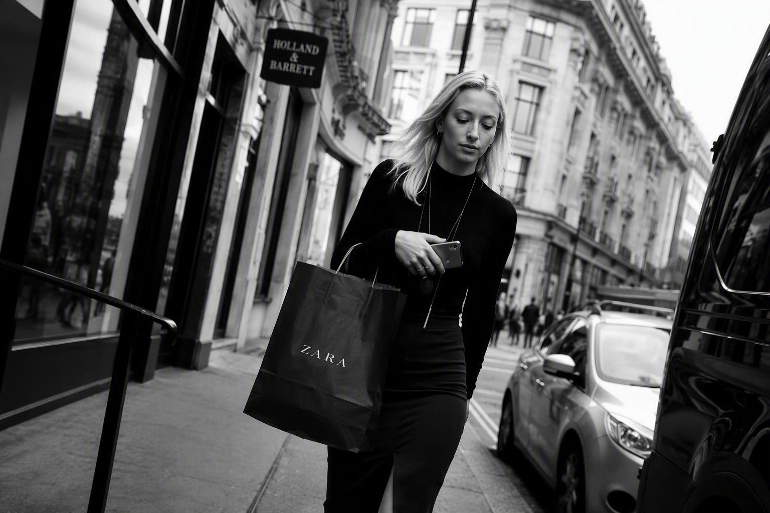 Woman walking along a London shopping street carrying a Zara bag, Holland & Barrett sign above her