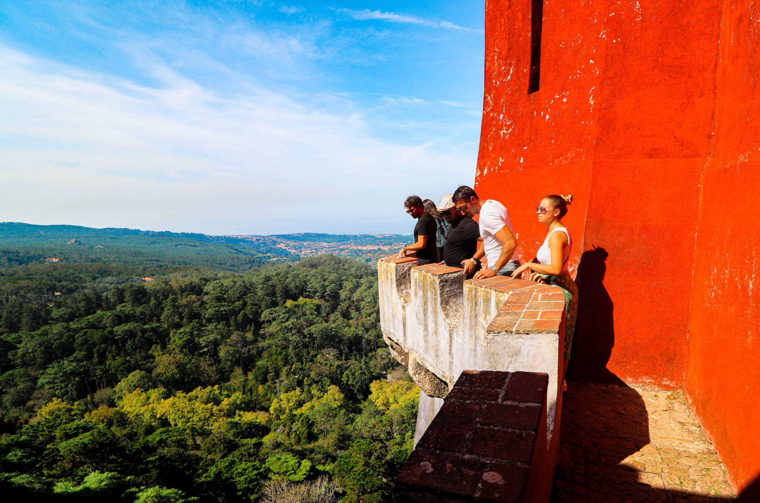 Visitors on the terrace of the red wing at Pena, Sintra, looking out over the forest toward the coast