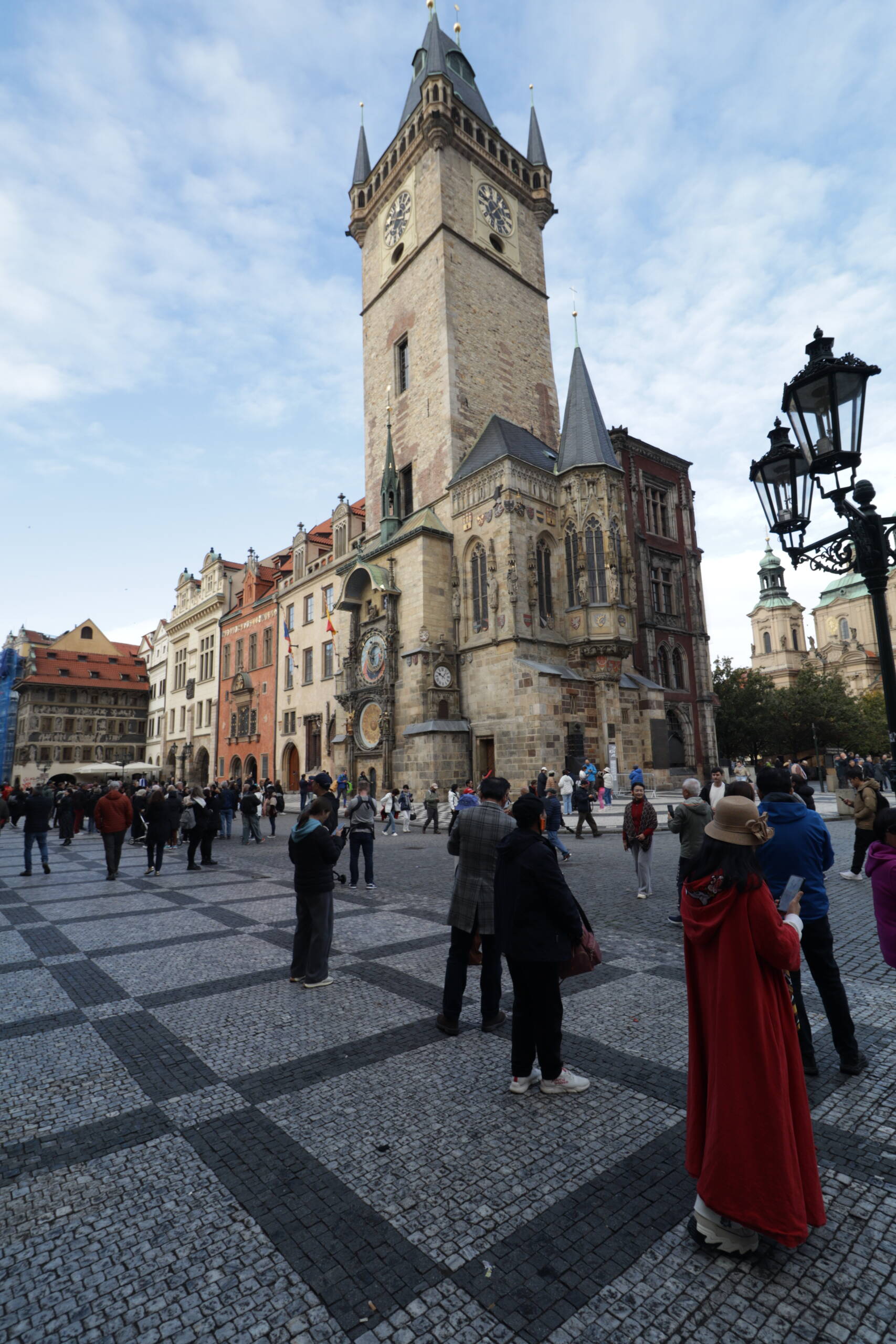 Prague Old Town Hall tower and the Astronomical Clock seen from the square, with checkerboard paving and a tourist crowd in the foreground